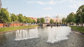 Ein öffentlicher Park mit einem Brunnen, Bänken und einem Gebäude mit einem Schild im Hintergrund.