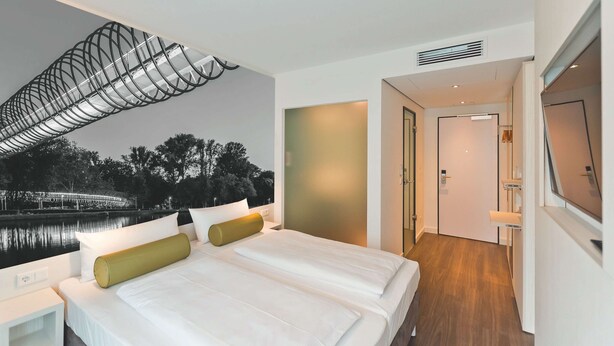 A modern hotel room with a large bed, a view of a bridge, and a wooden floor. - Super 8 by Wyndham Oberhausen am Centro (Oberhausen)
