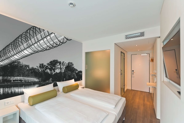 Een moderne hotelkamer met een groot bed, uitzicht op een brug en een houten vloer.