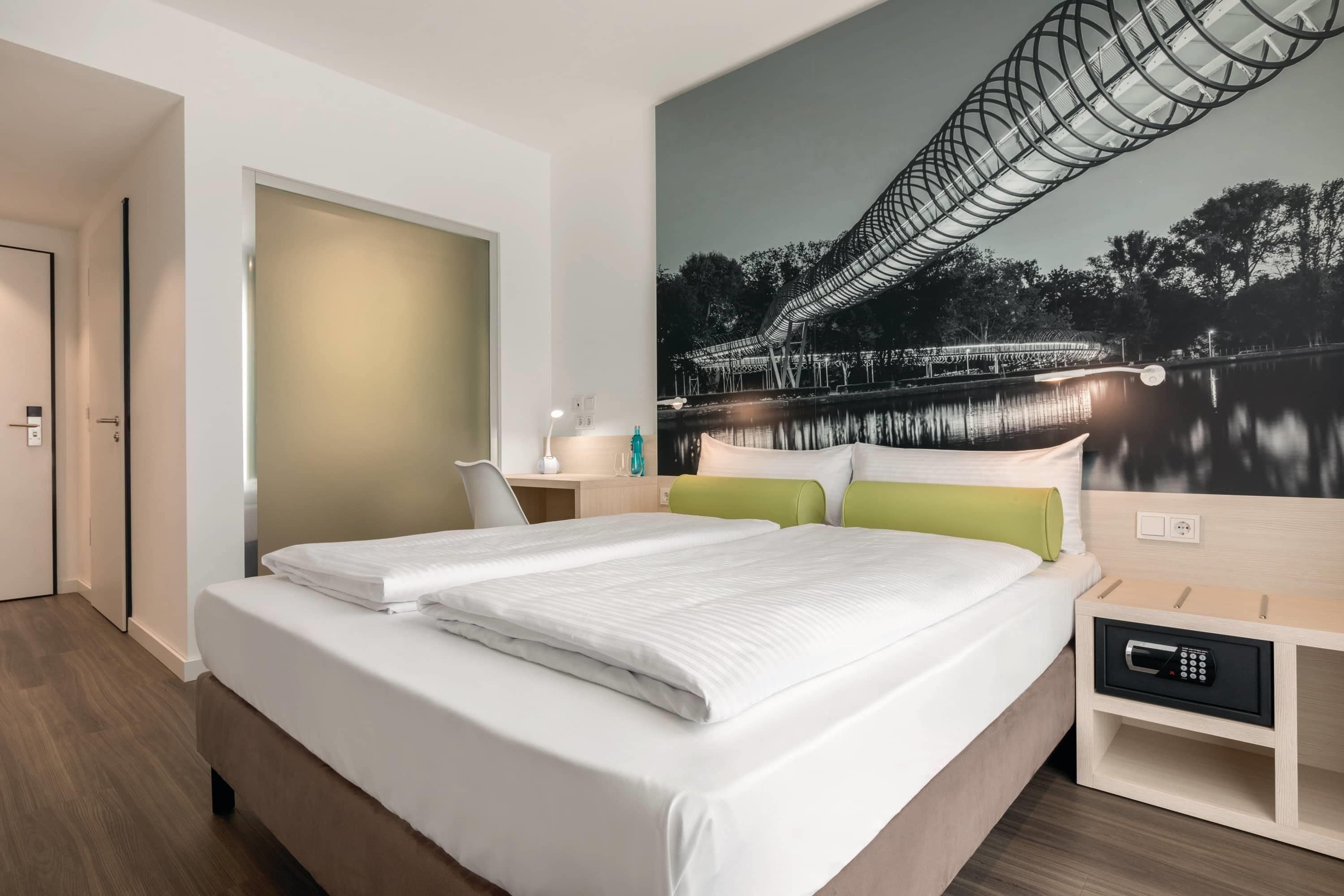 Ein Hotelzimmer mit einem großen Bett, einem Schreibtisch, einem Stuhl und einem an der Wand befestigten Fernseher.