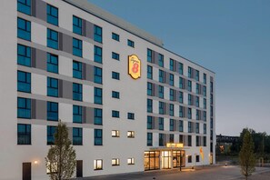Un hotel de varios pisos con un llamativo letrero de 'Super 8', ventanas grandes y una fachada plana.