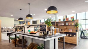 Een moderne keuken met een centraal eiland, hangende lampen en een krijtbordmenu.