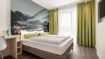 Een hotelkamer met een bed, een bureau, een stoel, een televisie en een muurschildering.
