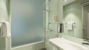 A modern bathroom with a glass shower enclosure, a white sink, and a large mirror. - Super 8 by Wyndham Oberhausen am Centro (Oberhausen)