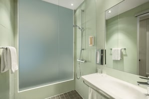 Een moderne badkamer met een douchecabine van glas, een wit wastafelmeubel en een grote spiegel.
