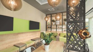 A modern reception area with a wooden reception desk, green seating, and decorative lighting. - Super 8 by Wyndham Oberhausen am Centro (Oberhausen)