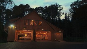 Eine Holzhütte mit großem offener Garage, mehreren Fenstern und einer Veranda mit Stühlen.
