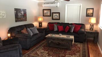 Relax in this stylish living room with a sofa, coffee table, side table, and lamp, surrounded by artwork and a large rug.