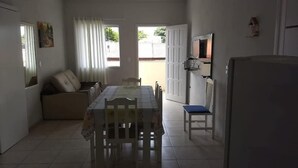 A compact kitchen with a dining table, chairs, a sofa, and a refrigerator. - Residencial Malu (Penha)