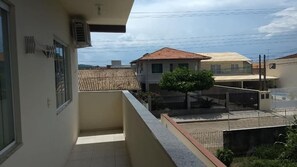 Ein Balkon mit Fliesenboden, Metallgeländer und Blick auf benachbarte Gebäude.