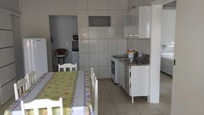 A compact kitchen with a dining table, chairs, a refrigerator, a microwave, and a sink. - Residencial Malu (Penha)
