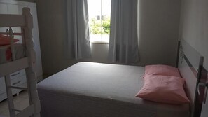 Ein Schlafzimmer mit einem Einzelbett, einem Holzbett mit Etagen und einem Fenster mit Vorhängen.