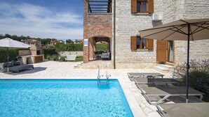 A swimming pool with lounge chairs and a pergola, surrounded by stone buildings and a clear sky. - Villa Paradis 6 - family villa with Pool (Butkovici)