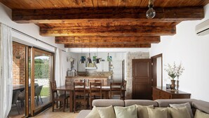 A cozy living room with a sofa, a dining table, and chairs. There is a kitchen area with a counter and cabinets. - Villa Paradis 6 - family villa with Pool (Butkovici)