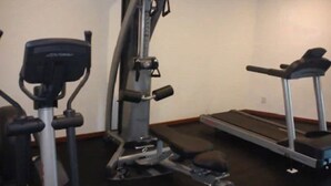 Un gimnasio con cinta de correr, elíptica y bicicleta estática.
