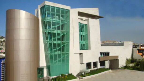 Un edificio moderno con una estructura cilíndrica a la izquierda y una fachada de vidrio a la derecha.