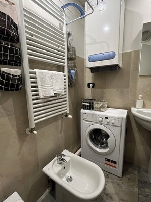 A bathroom with a white towel rack, a washing machine, a bidet, and a sink. - SCIESA 24 APARTMENTS - CIR 023091-LOC-01674 - CIN IT023091C2RKYIHNOG (Verona)