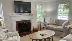 Una sala de estar con chimenea, televisor, sofá y mesa de centro.