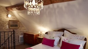 Ein Schlafzimmer mit einem großen Bett, einer Holzkommode, einem Nachttisch mit Lampe und einer Kristallleuchter.