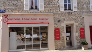 Ein Steinhaus mit einer Schaufensterfront, auf der “Boucherie Charcuterie Traiteur” steht.
