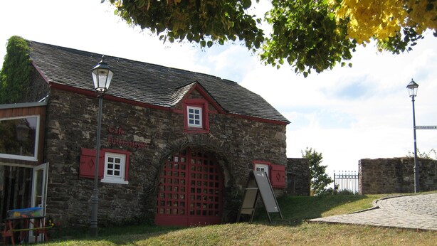 A stone building with a red door and windows, a small awning, and a street lamp.