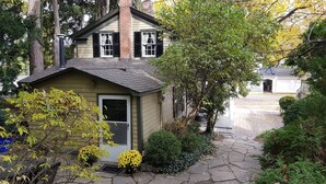 Ein kleines, eingeschossiges Haus mit einer Haustür, einem Schornstein und einer kleinen Veranda.