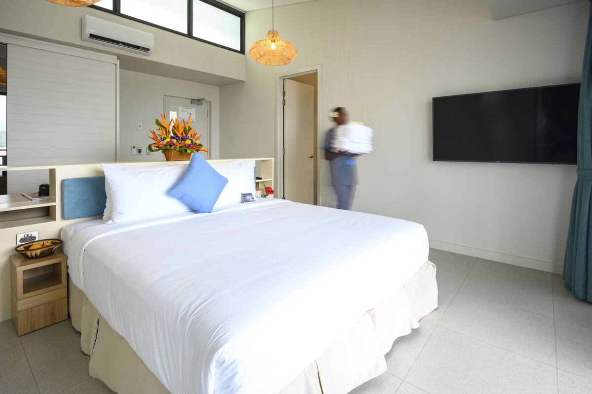 Une chambre d’hôtel avec un grand lit, un téléviseur à écran plat, une table de chevet et une petite table.