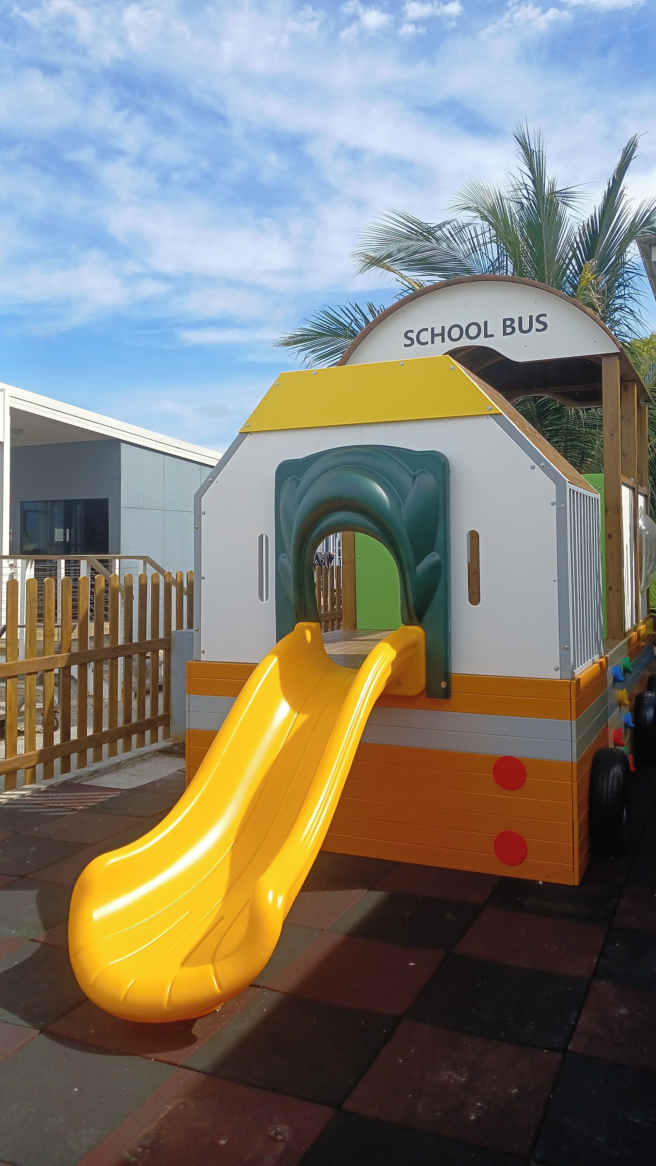 A school bus-themed play structure with a yellow slide.