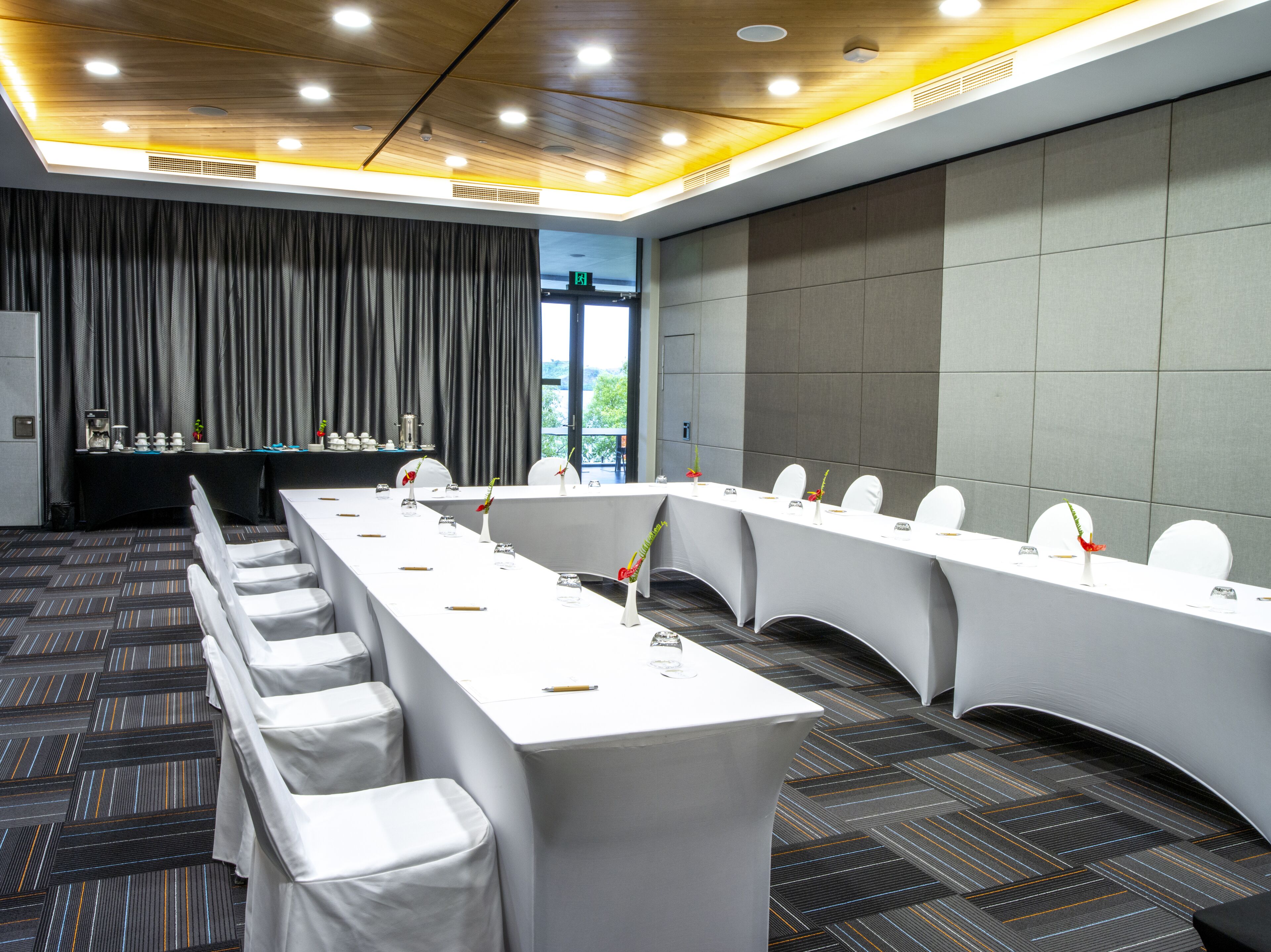 Una sala de conferencias con una mesa larga, sillas blancas y alfombra gris.