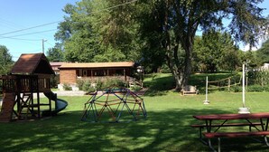 A playground with a swing set, a slide, and a climbing structure. - CREEKSIDE CABINS  - CHIPMUNK (Bryson City)
