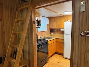 A compact kitchen with wooden cabinets, a stove, a sink, and a refrigerator.