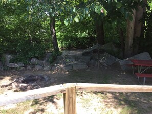 A natural outdoor area with a stone fire pit, wooden benches, and a hammock. - CREEKSIDE CABINS  - CHIPMUNK (Bryson City)