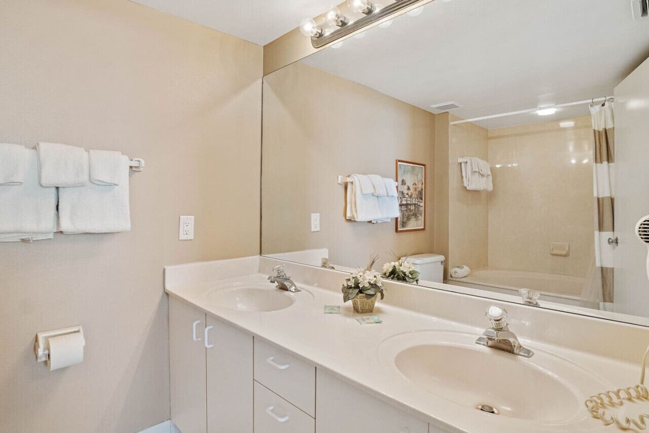 A bathroom with two sinks, a large mirror, and a shower.