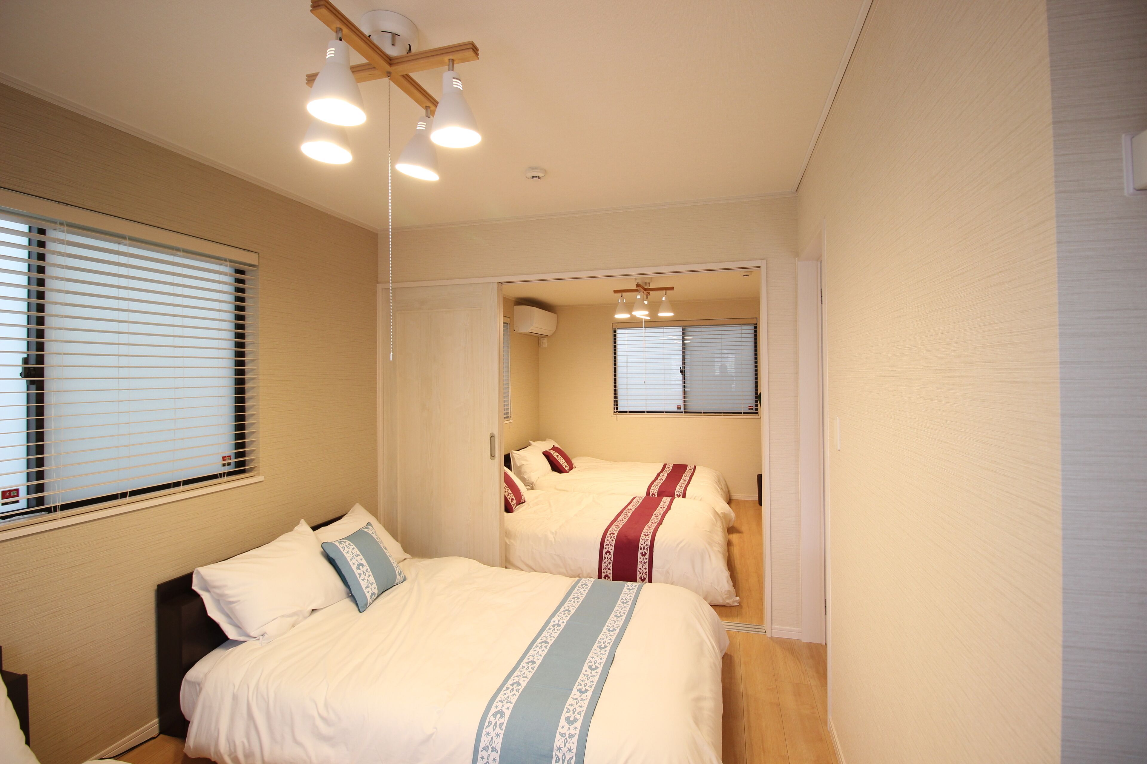 A bedroom with two beds, a ceiling fan, and a window with blinds.