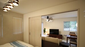 A hotel room with a bed, a desk, a chair, a television, and a ceiling fan. - Hope Villa Onnason (Onna)