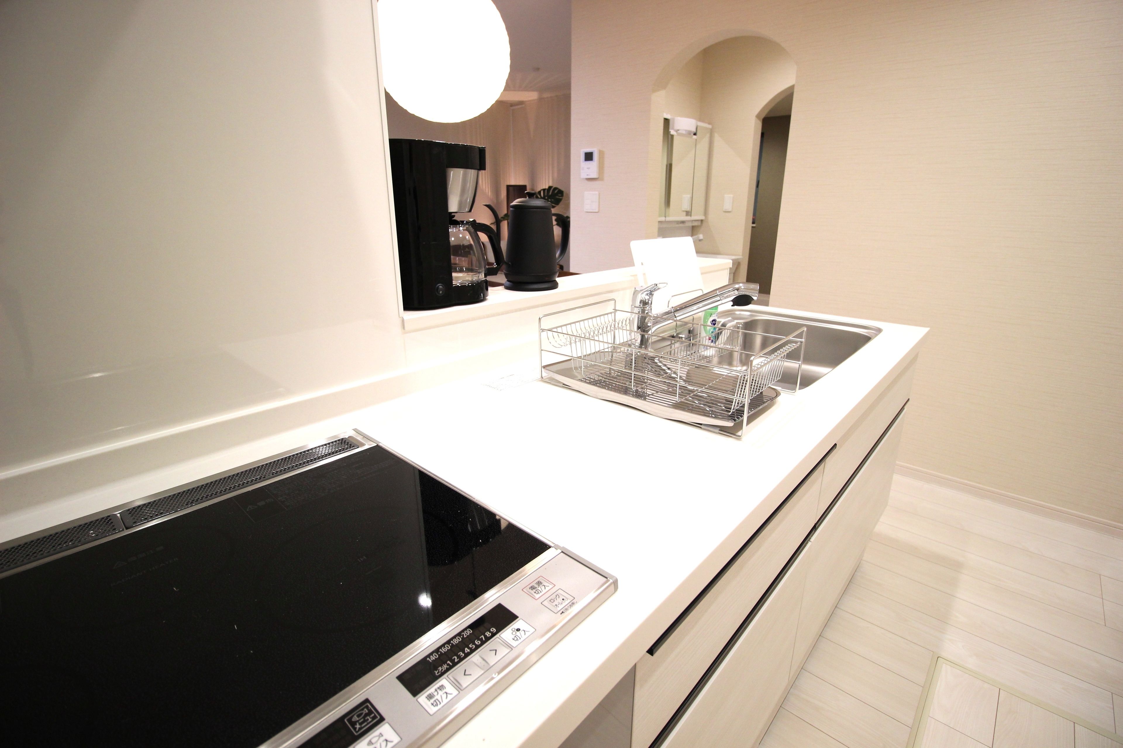 Una cucina moderna con piano cottura integrato, lavello con scolapiatti e specchio sopra il bancone.