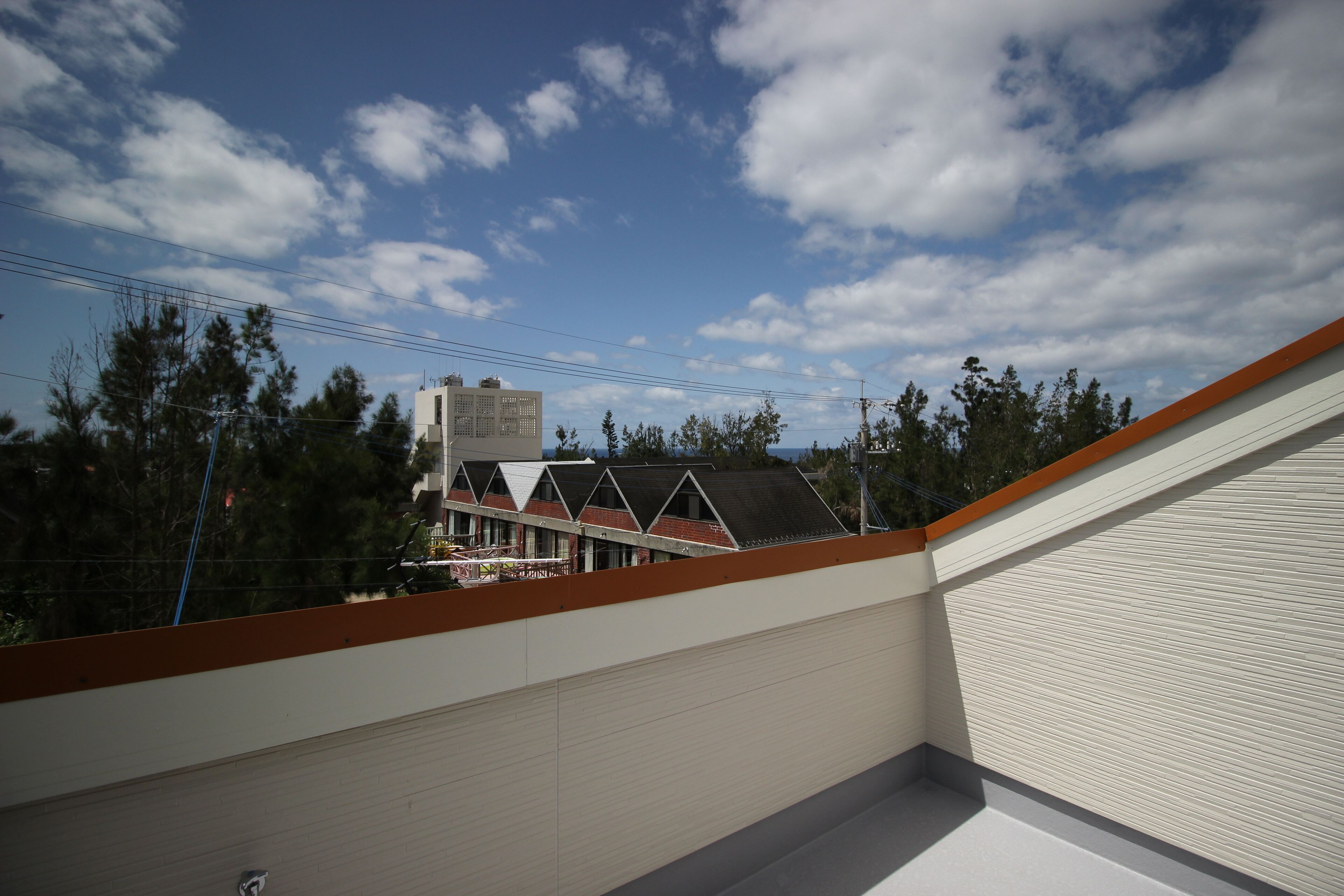 A rooftop with a view of a building with a triangular roof and a water tower in the background.