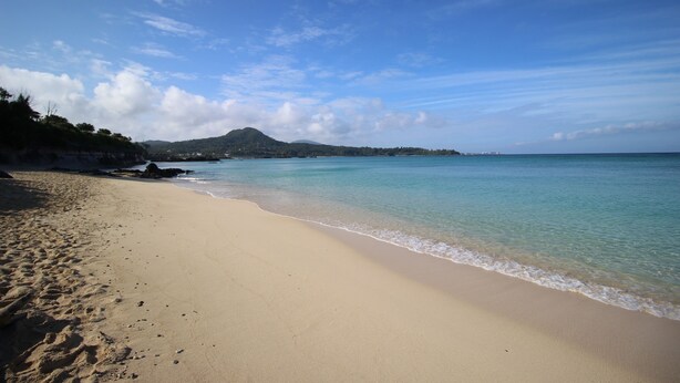 A beach with clear water, a sandy shore, and a distant mountain. - Hope Villa Onnason (Onna)