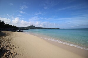 A beach with clear water, a sandy shore, and a distant mountain. - Hope Villa Onnason (Onna)