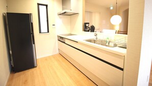 A modern kitchen with a black refrigerator, a built-in dishwasher, a stainless steel sink, and a coffee maker. - Hope Villa Onnason (Onna)