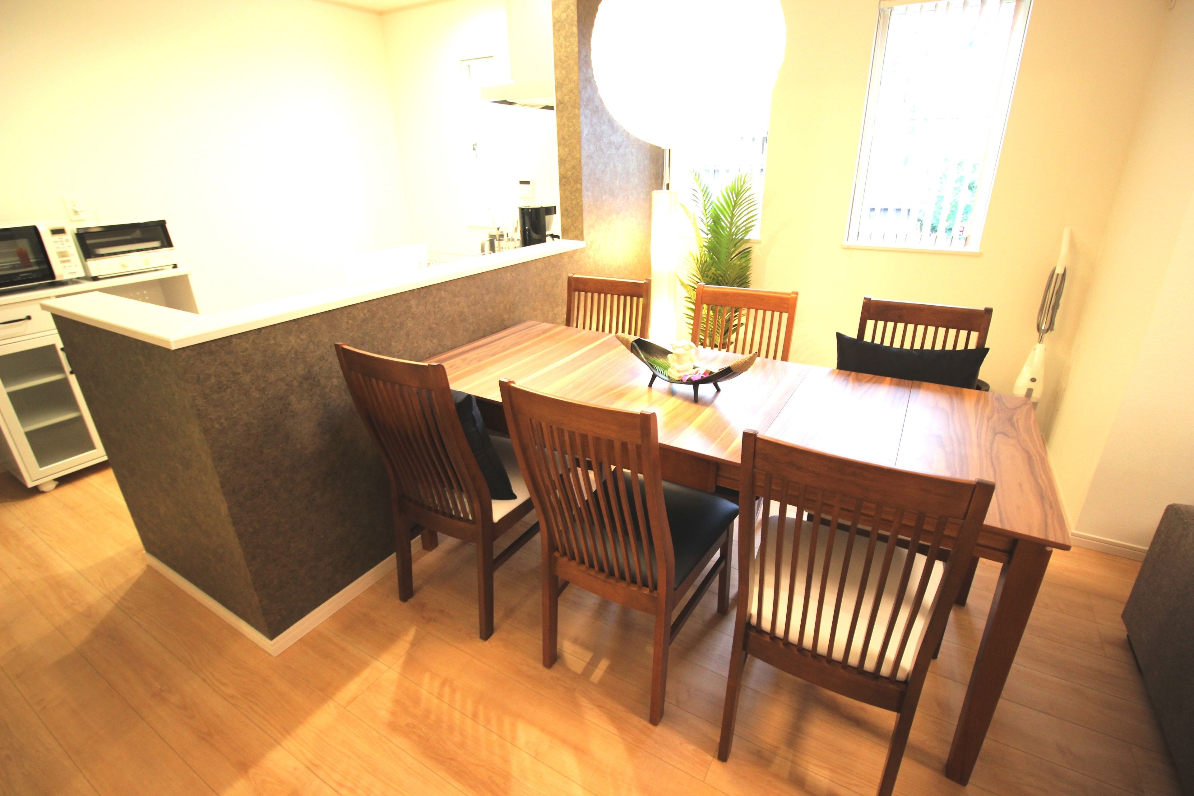 Una cocina compacta con comedor, sillas de madera, una pequeña isla y una planta en maceta.