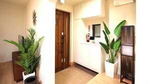 A modern kitchen with white cabinets, a wooden door, and a potted plant. - Hope Villa Onnason (Onna)