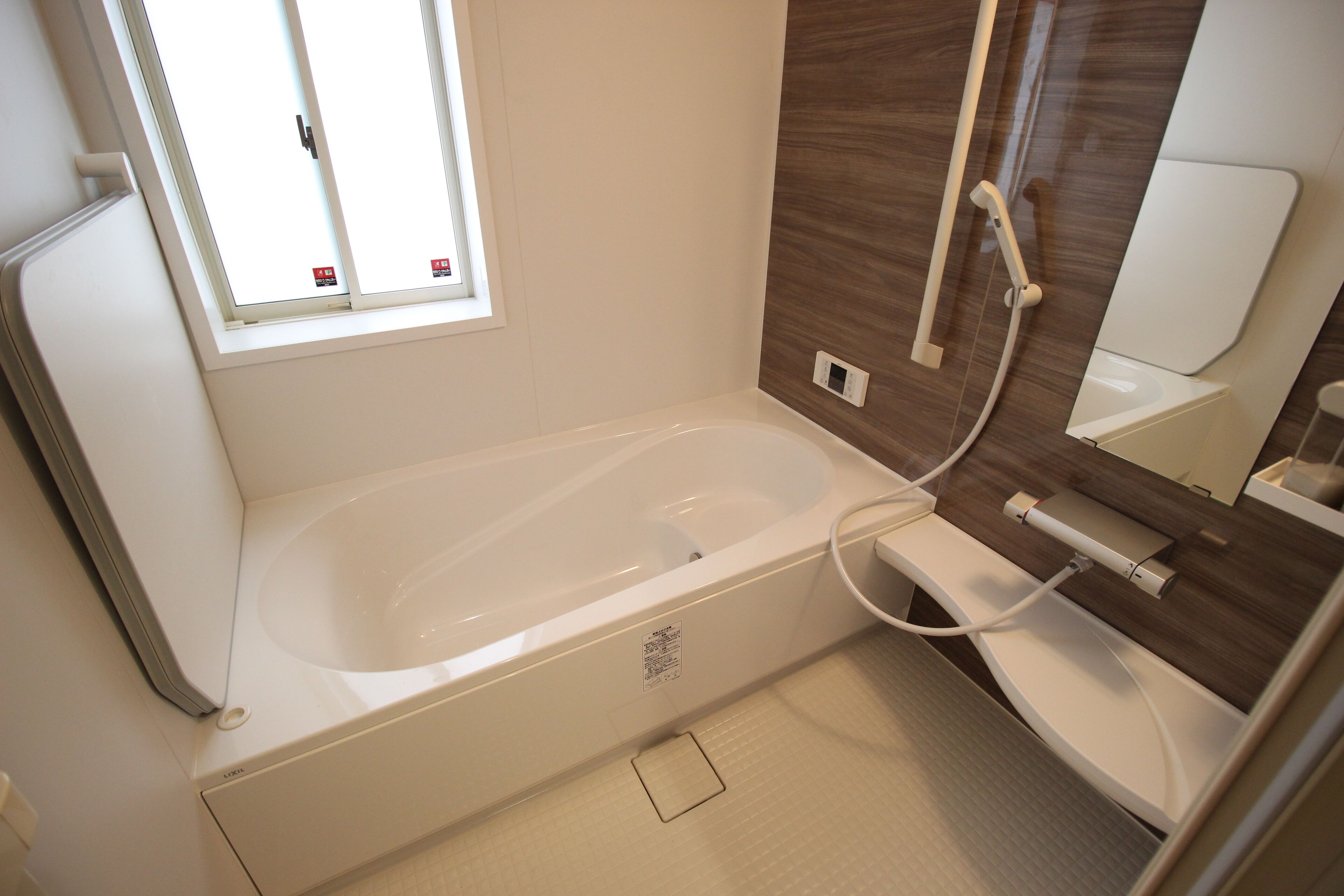 A modern bathroom with a bathtub, a window, a shower, and a mirror.