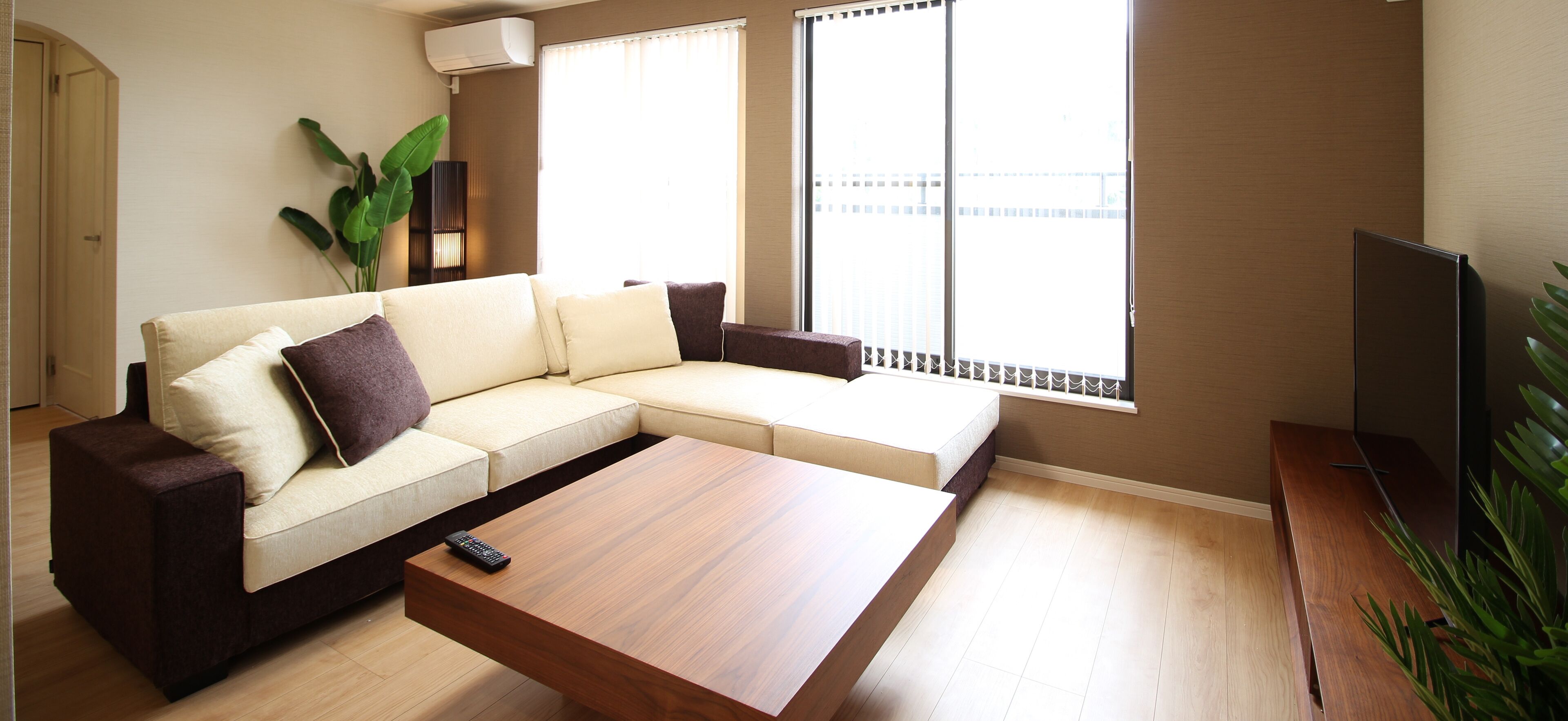 A modern living room with a sectional sofa, a coffee table, a TV, and a large window with a view.