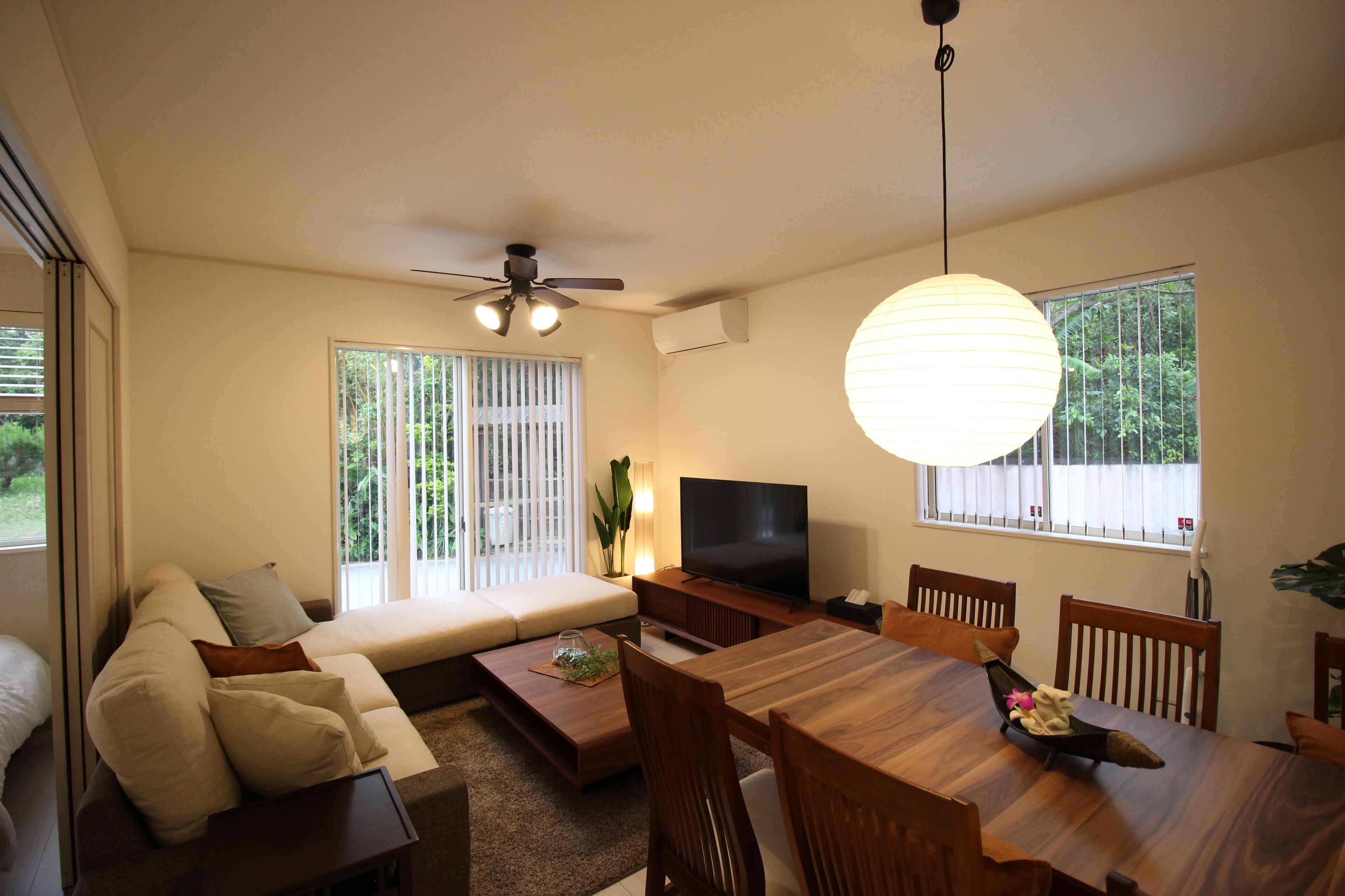 A modern living room with a sofa, TV, dining table, and chairs.