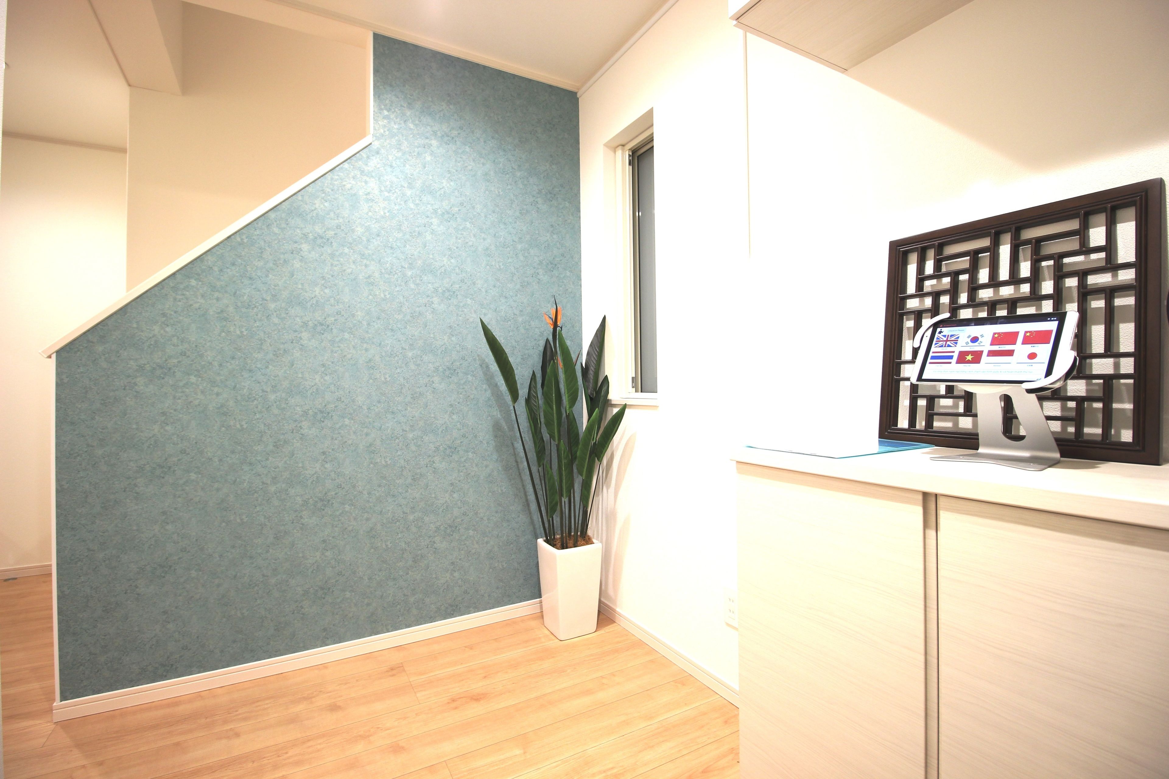 A reception area with a blue wall, a potted plant, and a digital display.