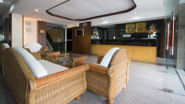 A lobby with wicker furniture, a reception desk, and framed artwork on the wall.