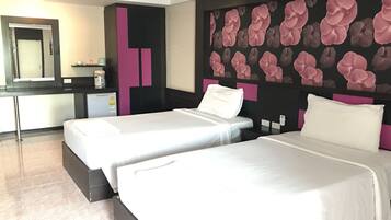 A hotel room with two beds, a large mirror, a minibar, and a floral wall design.