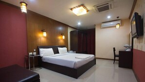 A hotel room with a large bed, a desk, a chair, and a television on the wall.