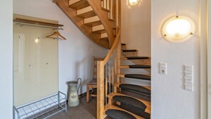Eine Holztreppe mit schwarzen Stufen, einem Metallgestell und einer Wandleuchte.